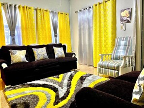Ein Wohnzimmer mit einem dunkelbraunen Sofa, einem gestreiften Sessel und einem gemusterten Teppich.