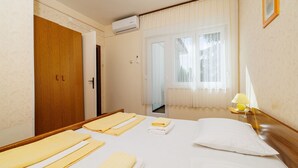 A hotel room with a bed, a bedside lamp, a window with curtains, and an air conditioning unit. - Dog-friendly apartment just 260 metres from the beach with sea views, barbecue (Dramalj)