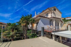 A multi-story building with balconies, a pool area, and surrounding palm trees. - Dog-friendly apartment just 260 metres from the beach with sea views, barbecue (Dramalj)