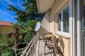 A balcony with a table and chairs, a satellite dish, and a view of neighboring buildings and trees. - Dog-friendly apartment just 260 metres from the beach with sea views, barbecue (Dramalj)