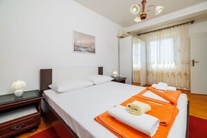 Ein Hotelzimmer mit einem großen Bett, einem Nachttisch, einer Lampe, einem Gemälde und einem Fenster mit Vorhängen.