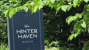 Schild für 'The HINTER HAVEN NORTH' mit einem Holzpfosten und umgeben von Grün.