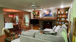 Ein Wohnzimmer mit Kamin, Fernseher und einem Essbereich mit Stühlen und Tisch.