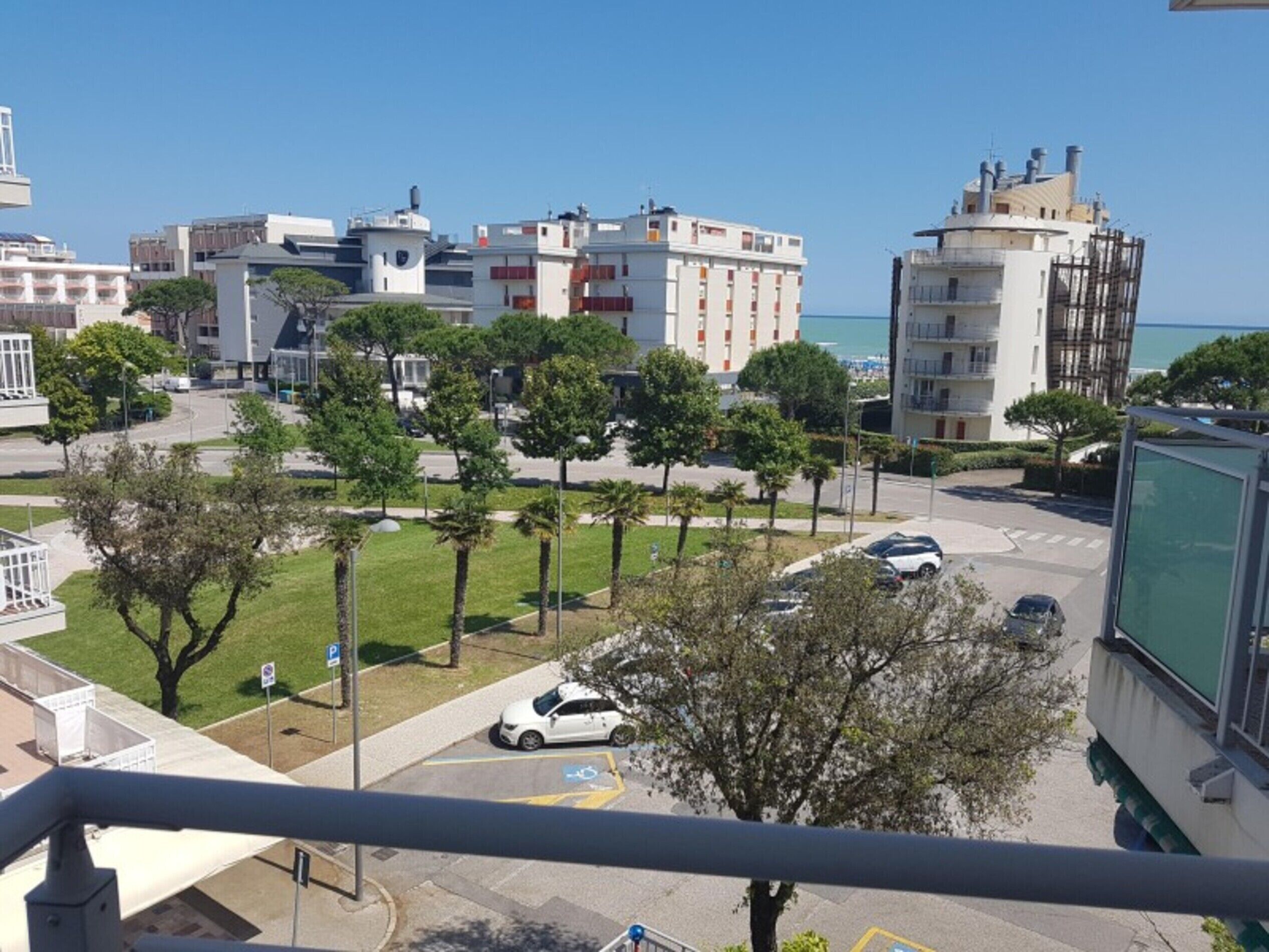 Zona residencial con aparcamiento, árboles y edificios al fondo.