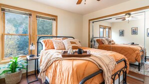 A bedroom with two beds, large windows, a ceiling fan, and a mirror. - Rustic In-Town Retreat | Pool | Hot Tub (Durango)