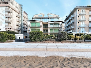A modern apartment building with multiple balconies, a rooftop terrace, and a landscaped garden area. - Seafront Apartment With Private Parking (Jesolo)