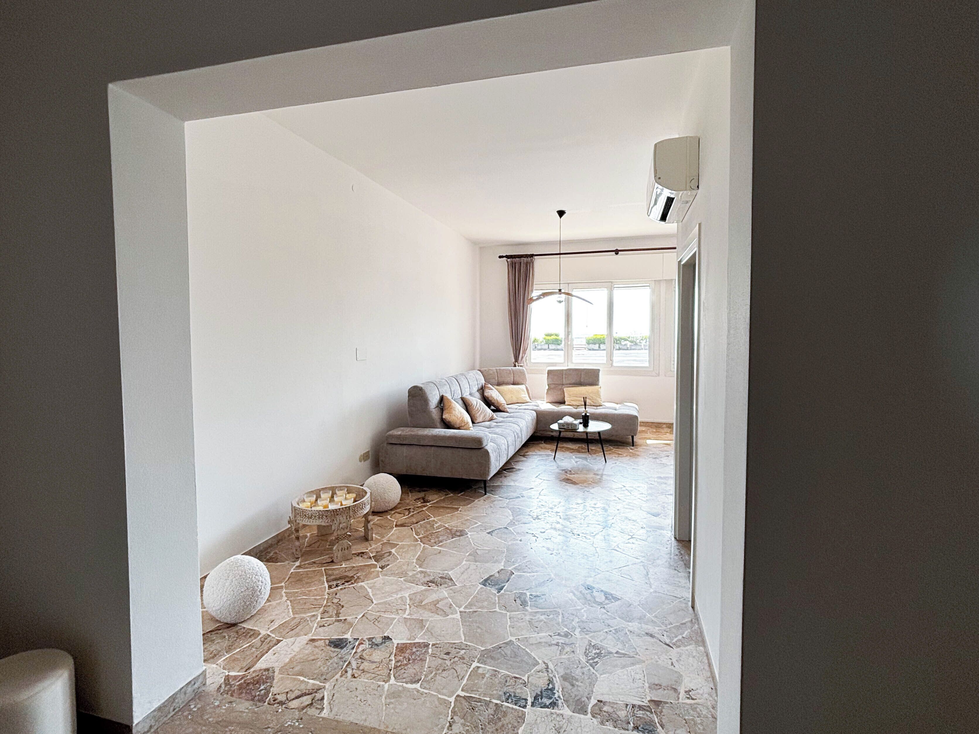 A modern living room with a grey sofa, a round coffee table, and a stone floor.