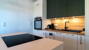 Eine moderne Küche mit Einbauherd, Backofen und Geschirrspüler, sowie einer Holzausziehtafel mit Spüle.