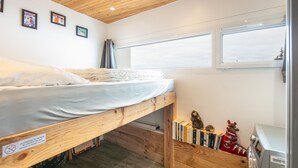 Un llit superposat amb matalàs, una petita prestatgeria amb llibres i joguines, i una màquina de rentar.