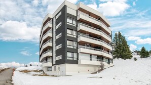 Un edifici de diversos pisos amb balcons, situat en una zona nevada amb cel serè.