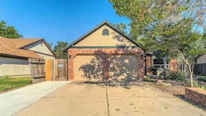 A single-story residential garage with a brick facade, a clear driveway, and a wooden fence on the left.