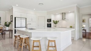 Una cocina moderna con una isla central, taburetes de bar y armarios blancos.