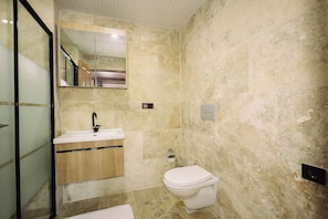 Et moderne badeværelse med en marmorvask, toilet og et stort spejl.