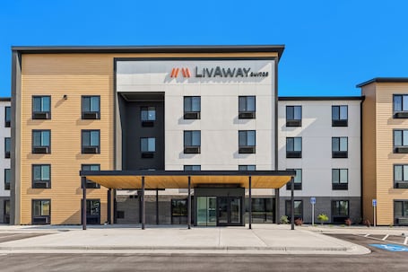 A modern building with a sign reading 'LIVAWAY SUITES' and a covered entrance.