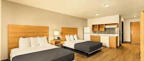 A hotel room with two beds, a kitchenette, and a separate bathroom.