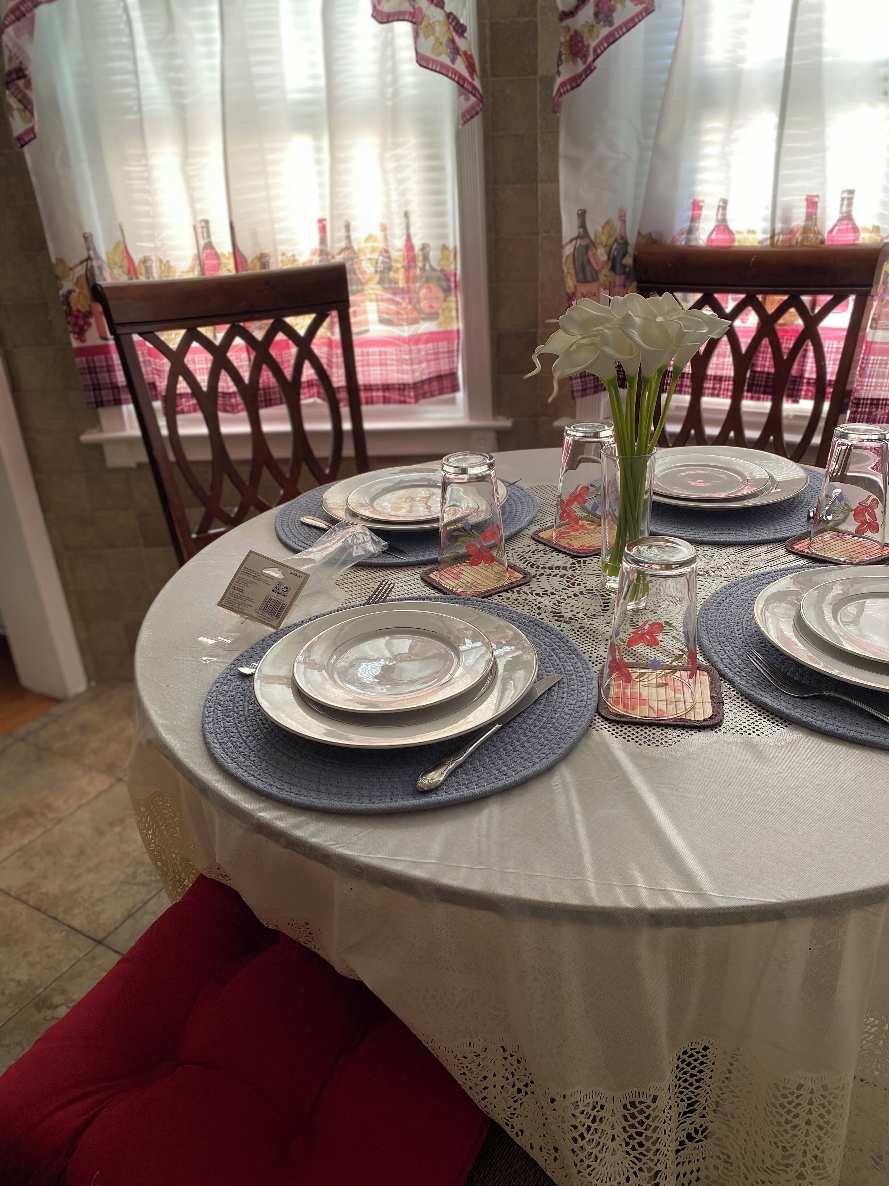 A dining table set with plates, cutlery, and a vase with flowers.