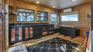 A modern kitchen with wooden walls, large windows, and a black and gold patterned rug. - The Time Machine Treehouse (Rockbridge)
