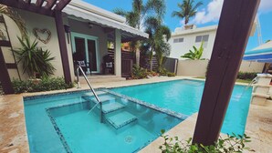 A swimming pool with a tiled edge, a wooden deck, and a covered patio area with a heart-shaped decoration. - Playa Cañones / Margarita Beach House / Private / Heated Pool (Aguada)