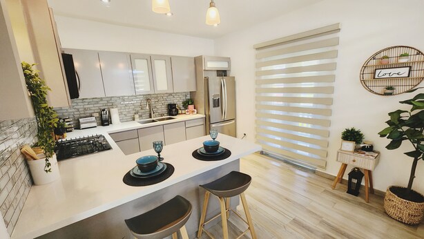 A modern kitchen with a central island, bar stools, a built-in oven, and a refrigerator. - Playa Cañones / Margarita Beach House / Private / Heated Pool (Aguada)