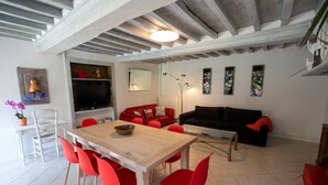 A dining area with a wooden table and red chairs, a black sofa, and a red armchair.