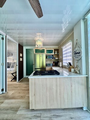 A modern kitchen with a central island, wooden cabinets, and a chandelier. - Hotel boutique style Indoor and outdoor living n apart in Mar Chiquita with a/c (Manatí)
