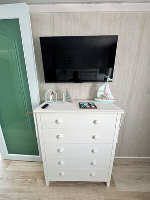 A white dresser with drawers, a flat-screen TV mounted on the wall, and a small decorative sailboat. - Hotel boutique style Indoor and outdoor living n apart in Mar Chiquita with a/c (Manatí)