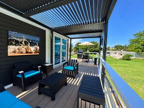 An outdoor deck with furniture, a glass door leading to a patio, and a view of a backyard. - Hotel boutique style Indoor and outdoor living n apart in Mar Chiquita with a/c (Manatí)