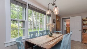 A dining area with a wooden table, blue chairs, and a vase of dried flowers. - Rush Pond Retreat at Goose Rocks Beach (Kennebunkport)