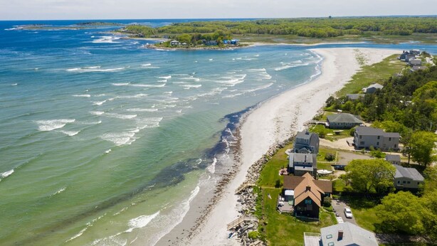 An aerial view of a coastal area with a beach, houses, and a lighthouse in the distance. - Rush Pond Retreat at Goose Rocks Beach (Kennebunkport)