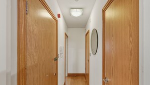 Un corridoio stretto con porte in legno e un lampadario a soffitto.