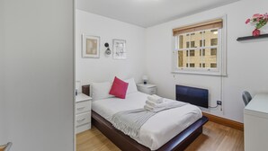 Una camera da letto ordinata con un letto, comodini, una scrivania e una finestra con vista.
