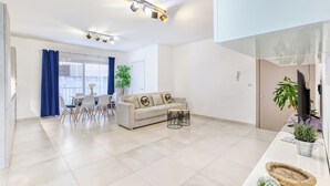 A modern living room with a sofa, coffee table, and dining area. - Central Msida | Modern, Bright & Comfortable (Msida)