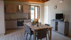 Una cocina con armarios de madera, estufa y comedor con mesa y sillas.