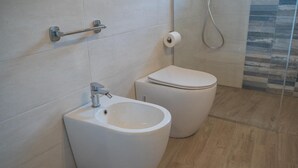 Un baño moderno con un bidé, inodoro y un perchero para toallas.