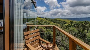 Ein Balkon mit Holzwertung, der einen üppigen Ausblick auf eine Landschaft mit Bergen im Hintergrund bietet.