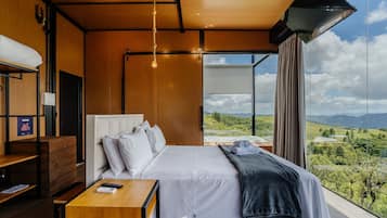 Un dormitorio moderno con una cama grande, muebles de madera y vistas a un paisaje.