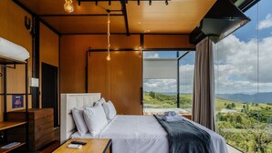 Ein modernes Schlafzimmer mit einem großen Bett, Holzmöbeln und Blick auf eine Landschaft.