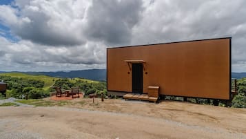 Un edificio moderno con fachada de madera, una puerta y un pequeño porche con sillas.