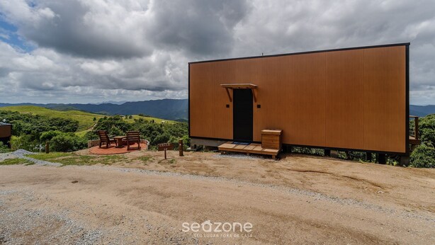 Ein modernes Gebäude mit Holzfassade, einer Tür und einer kleinen Veranda mit Stühlen.