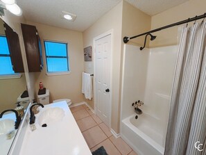 Un baño con lavamanos blanco, bañera y cortina de ducha.