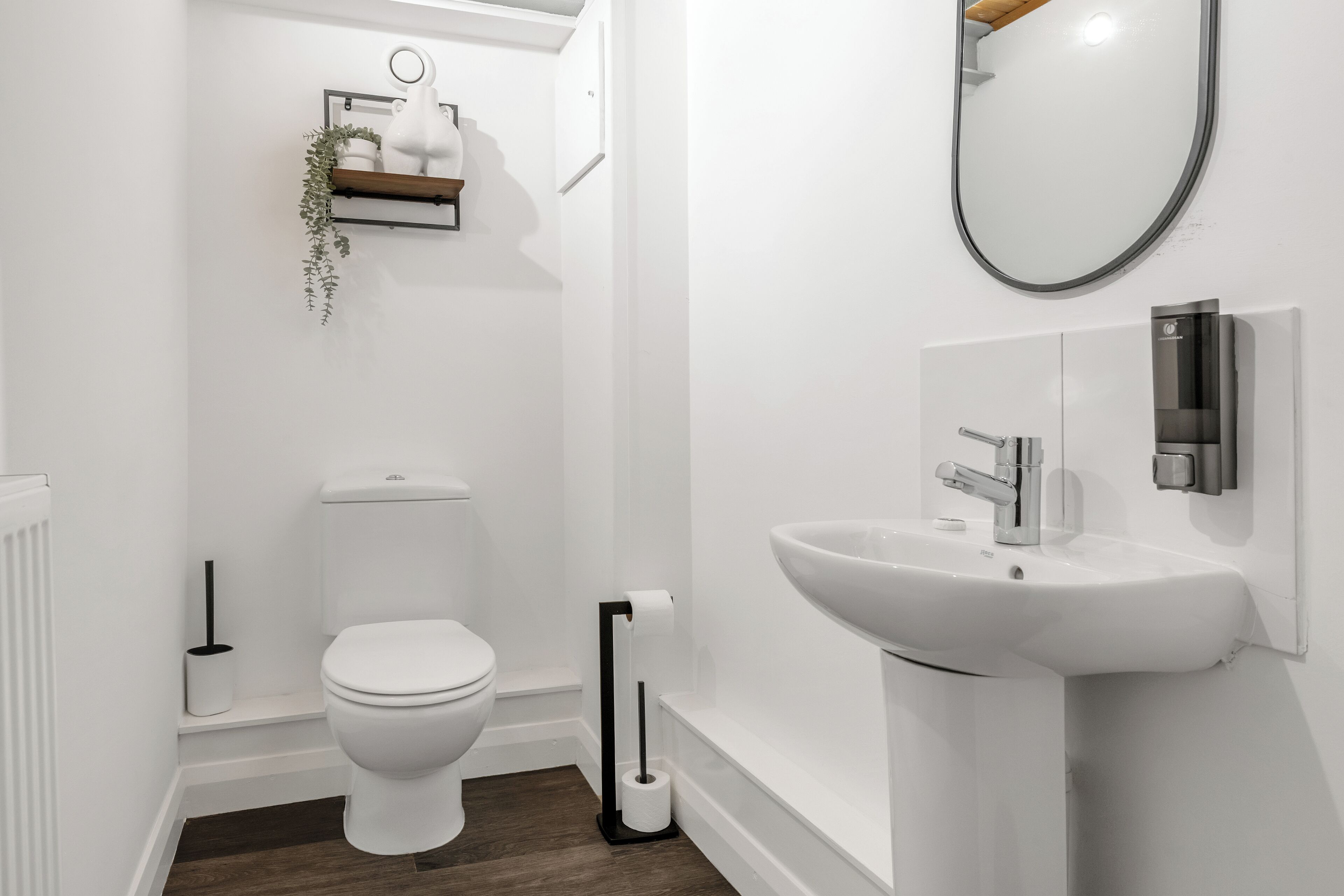 A modern bathroom with a white toilet, a white sink, and a mirror.