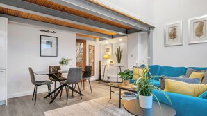 A modern living room with a blue sofa, a dining table with chairs, a coffee table, and a potted plant. - Central Apt Old Market Sqr with Parking (Nottingham)