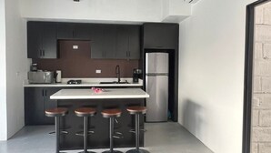Una cucina moderna con isola centrale, sgabelli da bar e frigorifero.