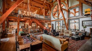 Ein großzügiger Holzraum mit hoher Decke, einem Essbereich, einem Wohnbereich mit Sofas und einer Treppe zu einer oberen Ebene.