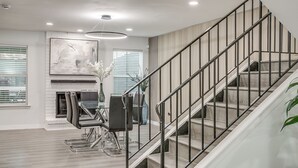 Un interior moderno con una escalera, chimenea y comedor.