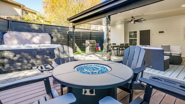 Un patio exterior con una mesa redonda, sillas, una parrilla y un jacuzzi.