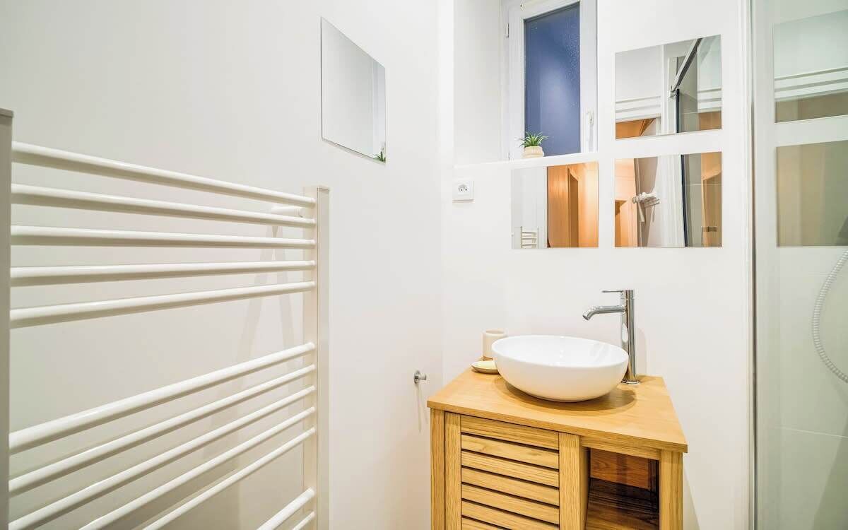 Een moderne badkamer met een witte badkuip, een houten wastafelmeubel met een wastafel en een spiegel boven de wastafel.
