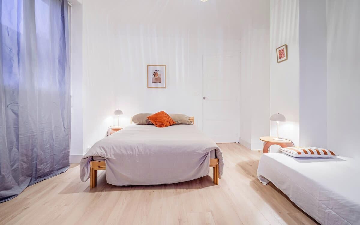 Una camera da letto con un letto, due comodini e una finestra con tende.