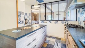 Una cucina moderna con una grande isola, forno a incasso e una parete attrezzata con motivi geometrici.