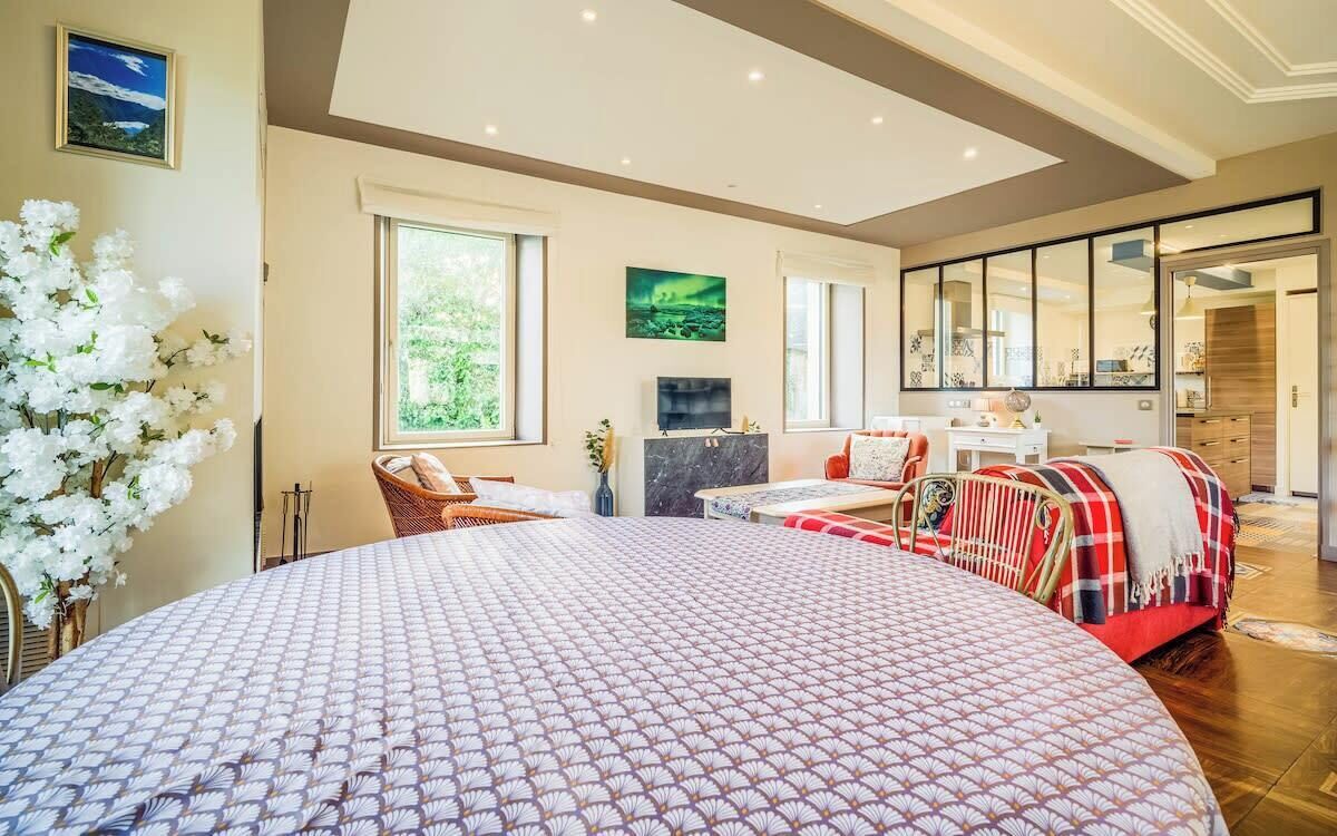 Un dormitorio amplio con una cama grande, una zona de estar con sofá y sillones, una chimenea y vistas al exterior a través de amplios ventanales.